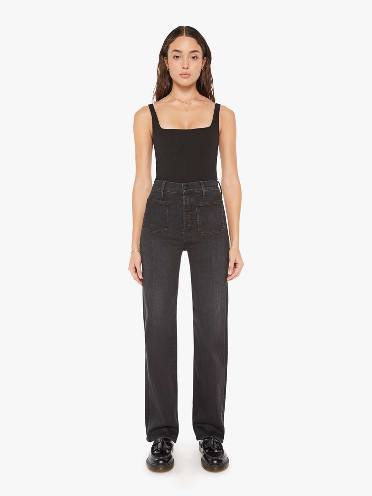 Front view of a woman black high-waisted jeans with a wide straight leg, patch pockets, zip fly and a long 32-inch inseam.
