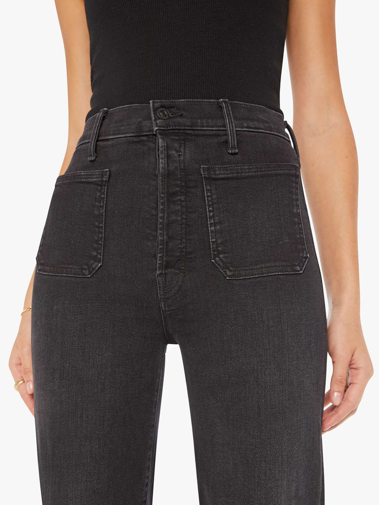 Waist close up view of a woman black high-waisted jeans with a wide straight leg, patch pockets, zip fly and a long 32-inch inseam.