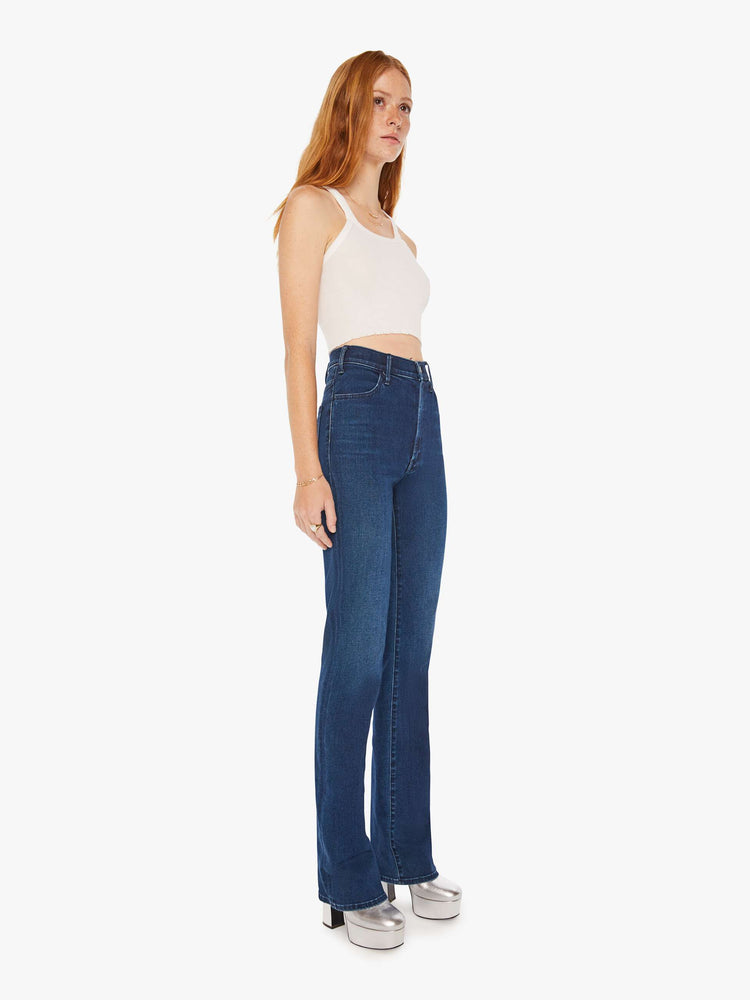 Side angle view of a woman dark blue wash high-waisted flare jeans with a long 34-inch inseam and a clean hem.