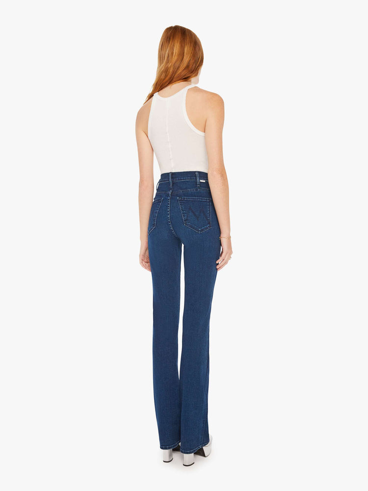 Back view of a woman dark blue wash high-waisted flare jeans with a long 34-inch inseam and a clean hem.