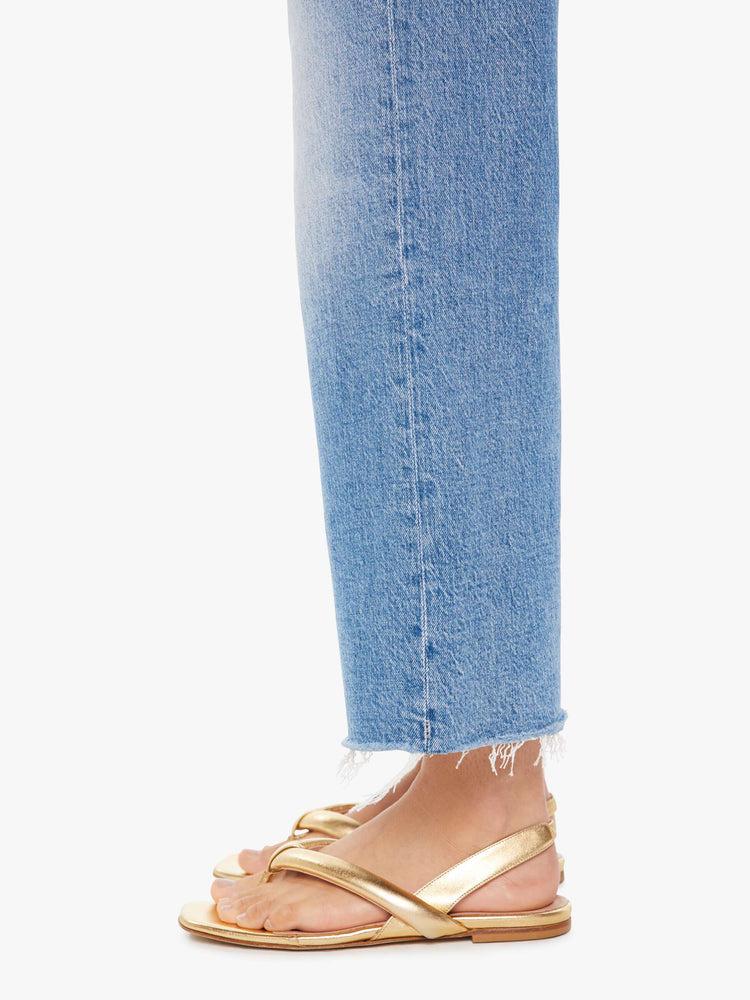 Side close up view of a woman wearing a medium blue wash jean featuring an angle length wide leg with frayed hem.