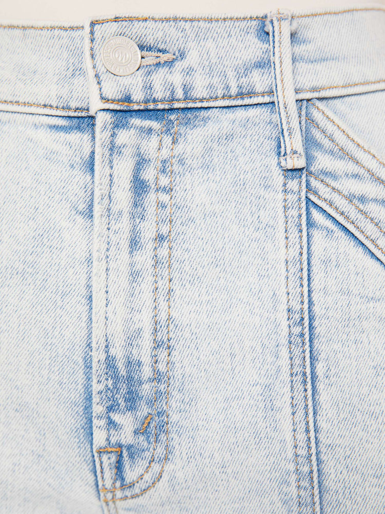 A close up swatch detail view of a light blue wash jean featuring darker blue hues around the seams.