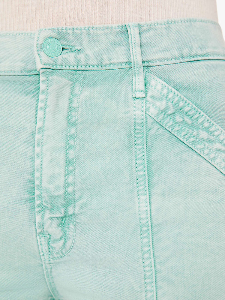 A close up swatch view of a light teal wash pant with darker teal hues around the seams, featuring tonal hardware and stitching.