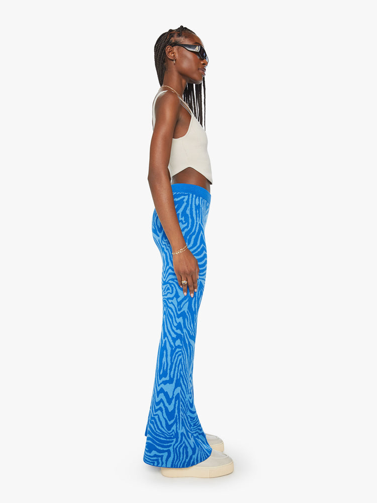 Side view of a woman high-waisted wide-leg flare with an elastic waist and a 31-inch inseam in blue zebra print.