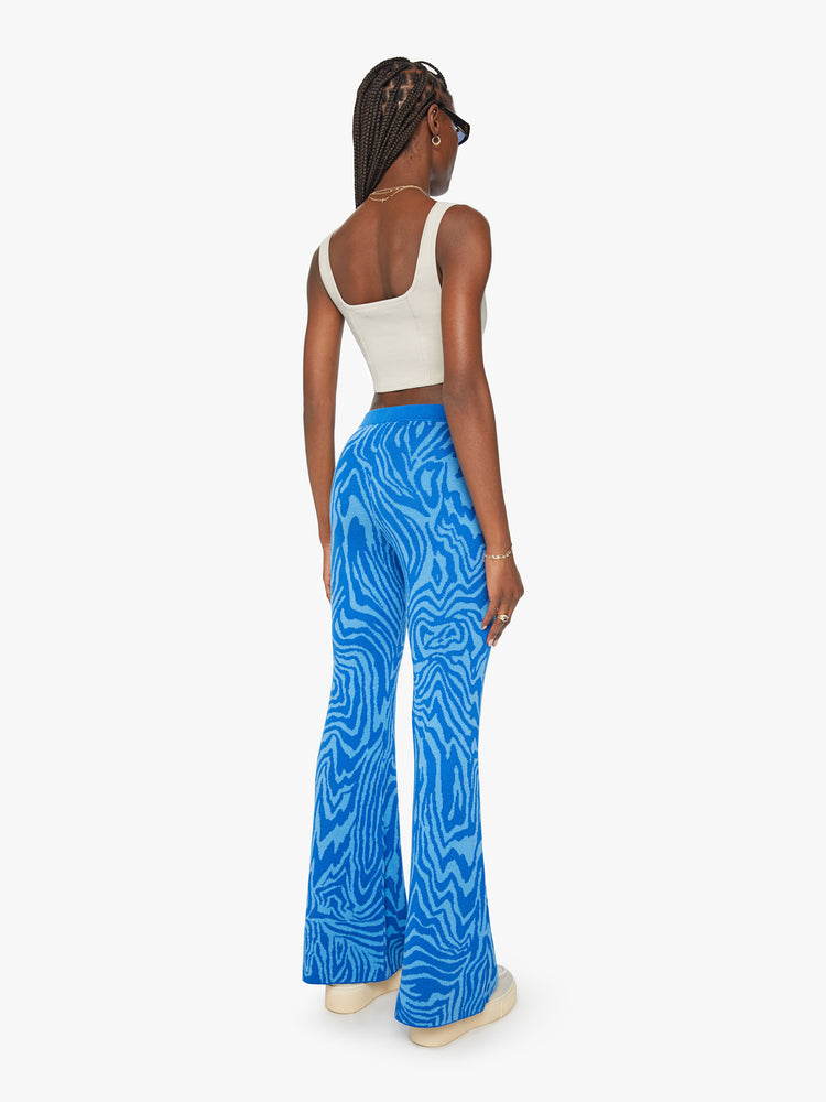 Back view of a woman high-waisted wide-leg flare with an elastic waist and a 31-inch inseam in blue zebra print.