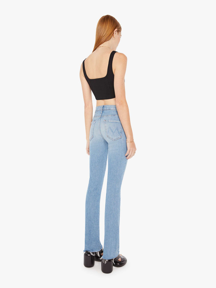 Back view of a womens light blue jean featuring a high rise and a frayed bootcut.