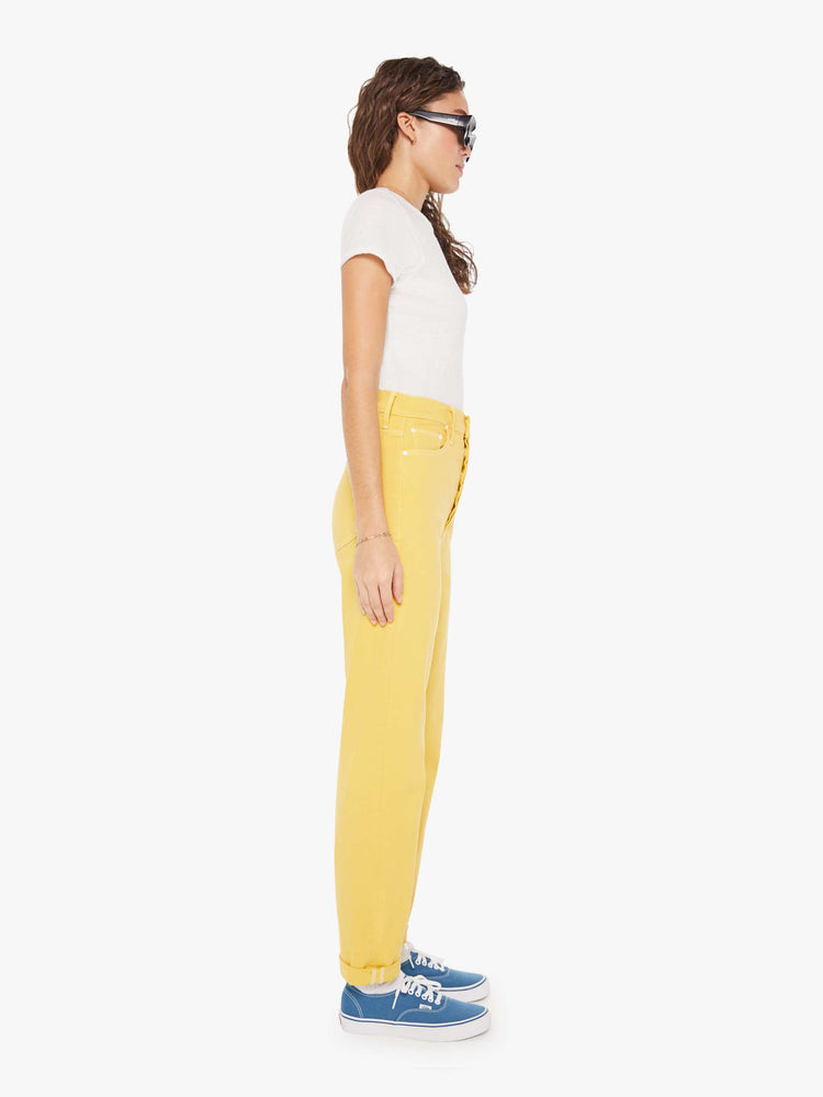 Side view of a womens yellow high rise jean featuring a cuffed hem.