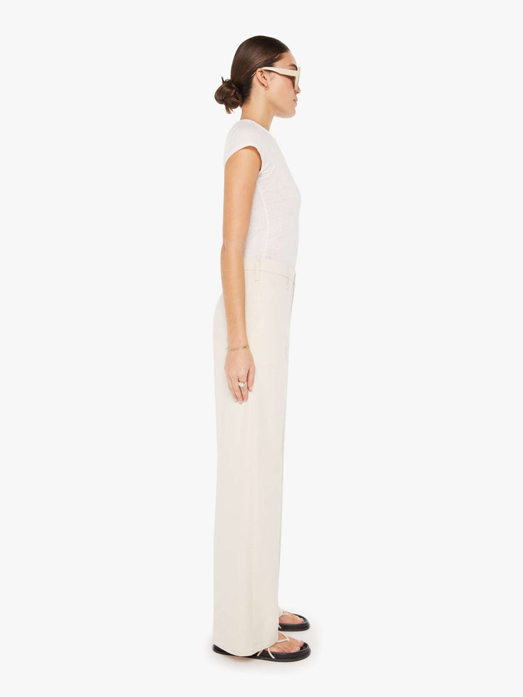 Side view of a womens ecru color pant featuring a relaxed mid rise, wide legs, and a clean full length hem.
