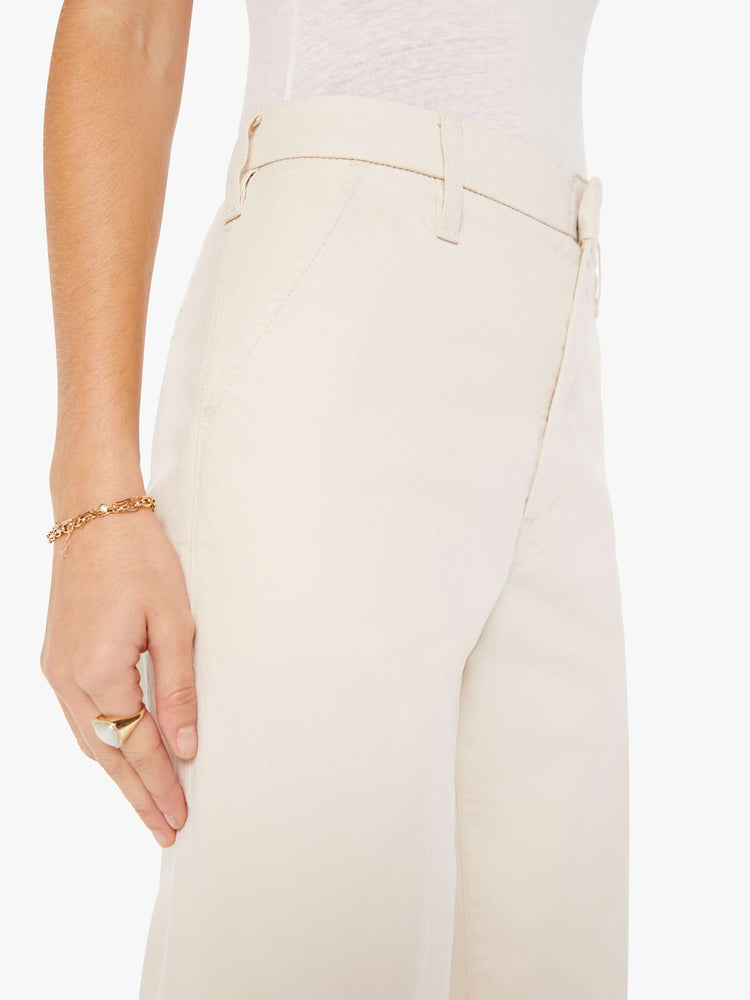 Side close up view of a womens ecru color pant featuring a relaxed mid rise, wide legs, and a clean full length hem.
