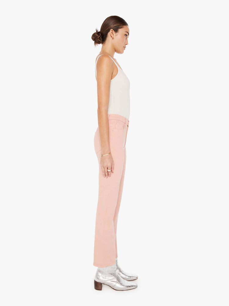 Side view of a womens faded pink jean featuring a high rise and a bootcut leg with clean hem.
