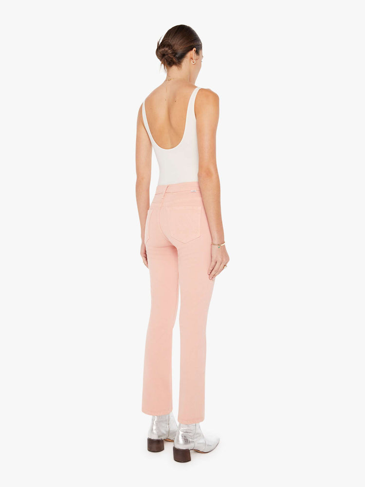 Back view of a womens faded pink jean featuring a high rise and a bootcut leg with clean hem.