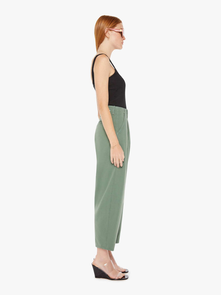 Side view of an army green pant featuring a super high rise with pleats, a wide leg, and a slightly tapered flood length hem.