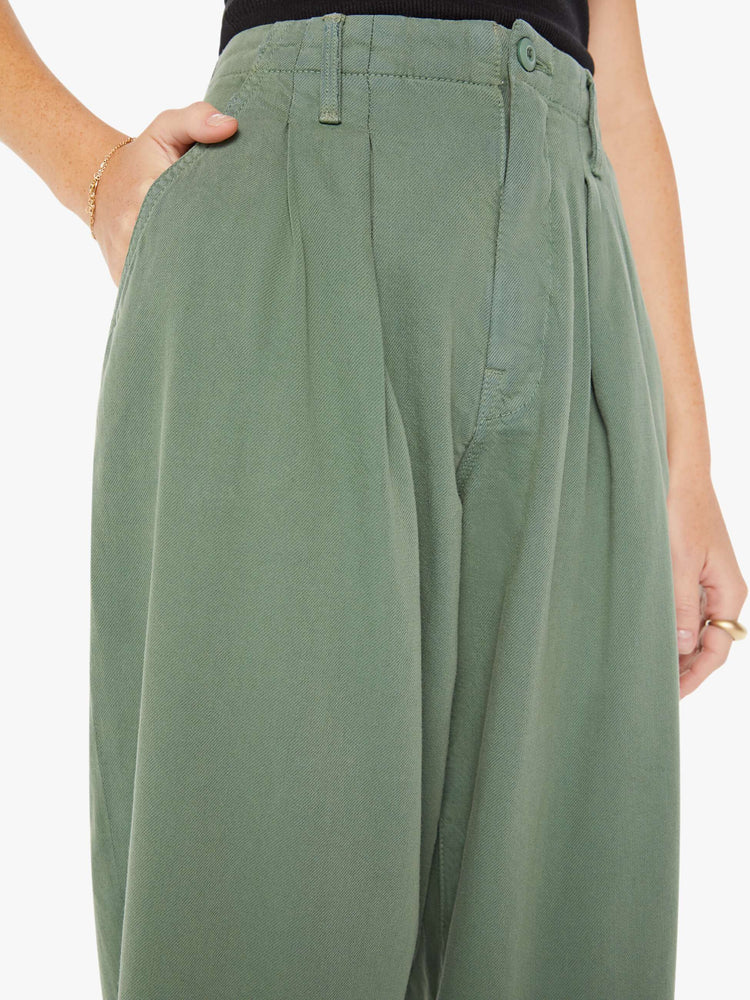 Front close up view of an army green pant featuring a super high rise with pleats, a wide leg, and a slightly tapered flood length hem.