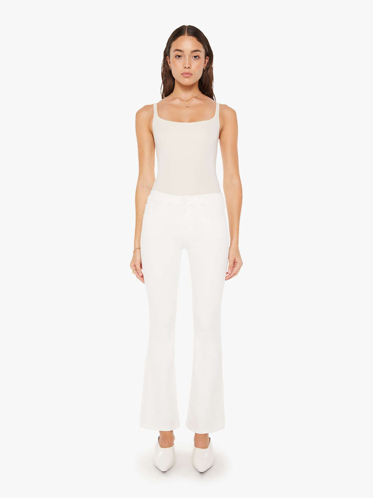 Front view of a woman white denim super low-rise flares have a 31-inch inseam and a clean hem.