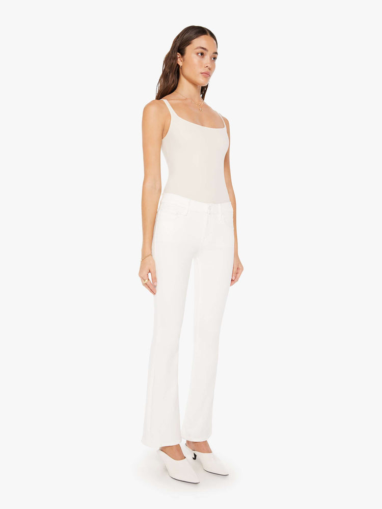 Side angle view of a woman white denim super low-rise flares have a 31-inch inseam and a clean hem.