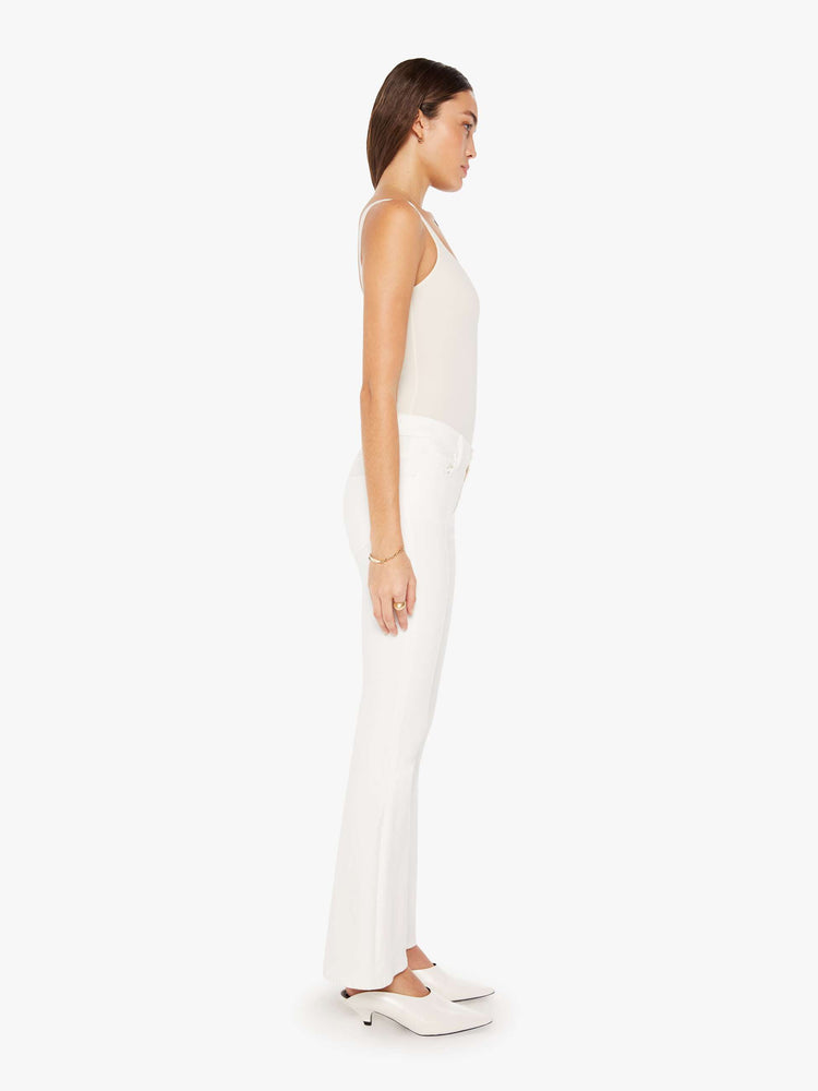 Side view of a woman white denim super low-rise flares have a 31-inch inseam and a clean hem.