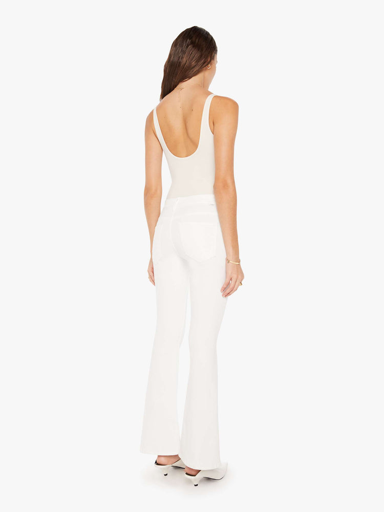 Back view of a woman white denim super low-rise flares have a 31-inch inseam and a clean hem.