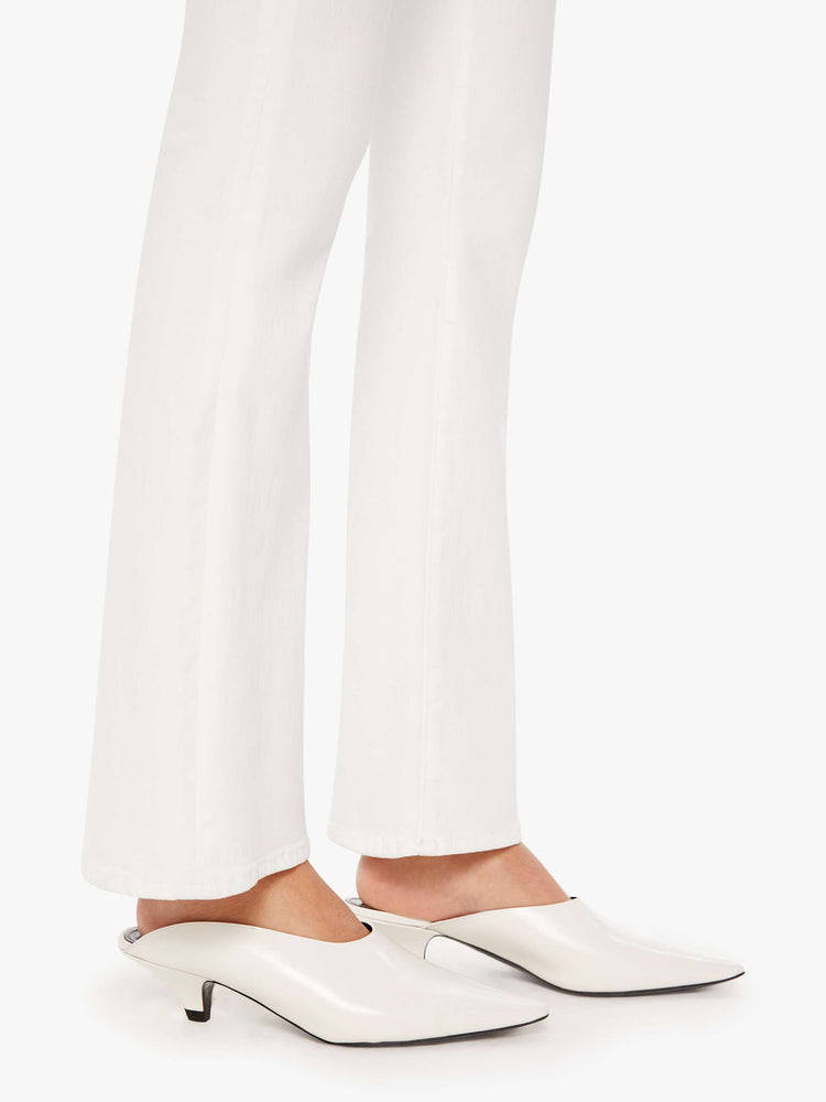 Hem view of a woman white denim super low-rise flares have a 31-inch inseam and a clean hem.