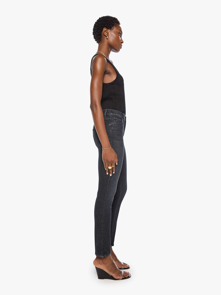 Side view of a woman in a black mid-rise straight leg jean with a zip fly, 31-inch inseam and a clean hem.