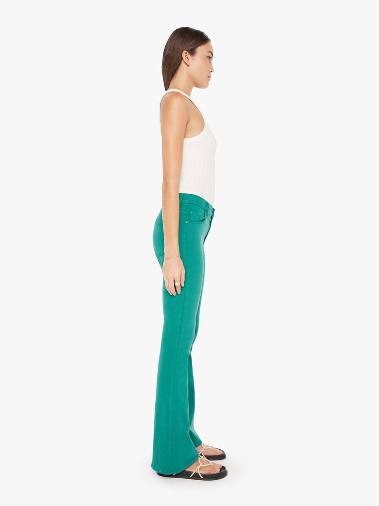 Side view of a womens teal pant featuring a mid rise and long flare leg.