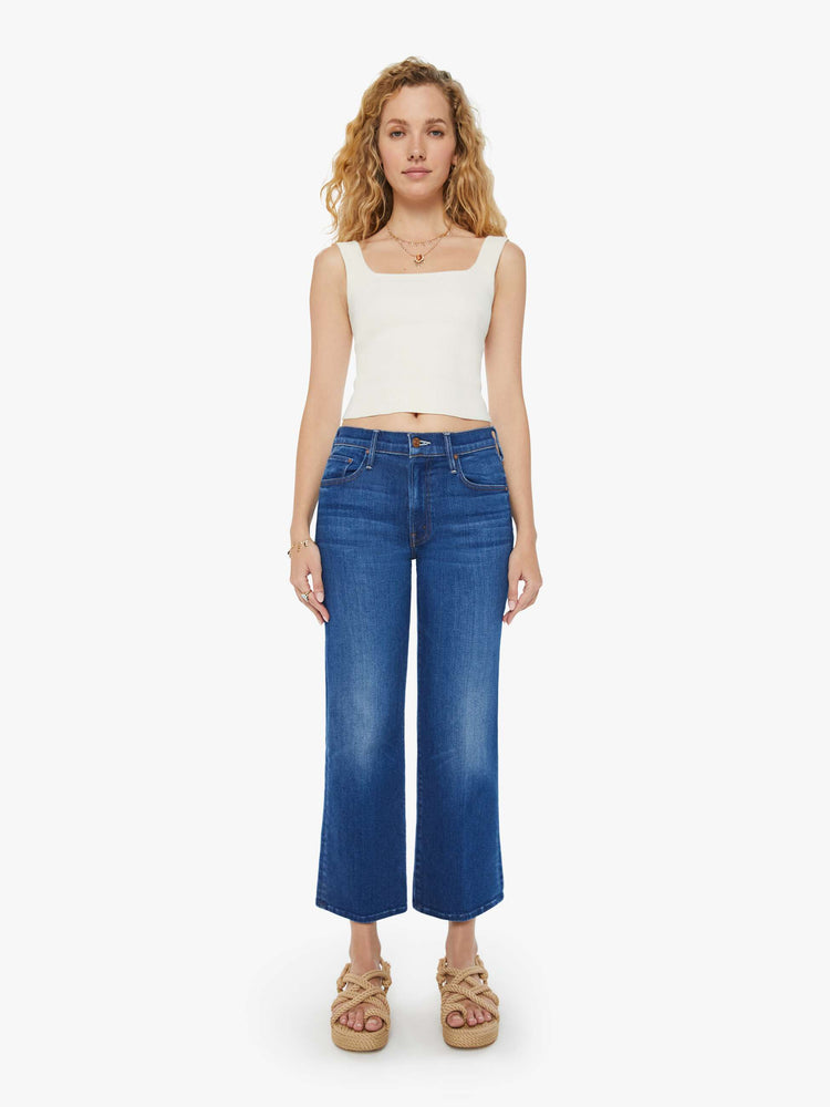 Front view of a woman in dark blue wide leg jeans with super subtle whiskering and fading at the knees. Styled with a white tank top.