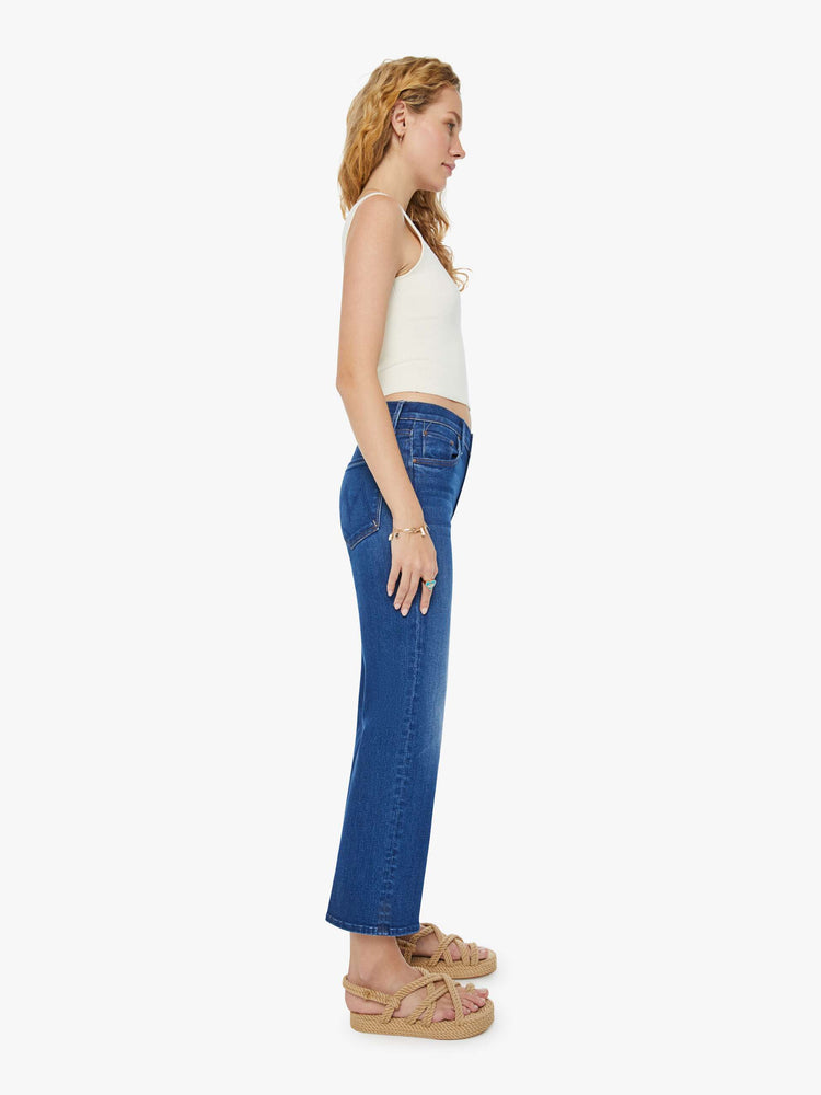 Side view of a woman in dark blue wide leg jeans with super subtle whiskering and fading at the knees. Styled with a white tank top.