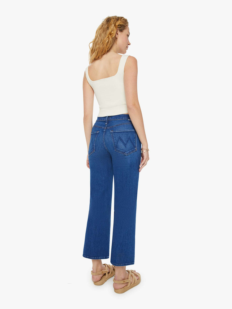 Back view of a woman in dark blue wide leg jeans with super subtle whiskering and fading at the knees. Styled with a white tank top.