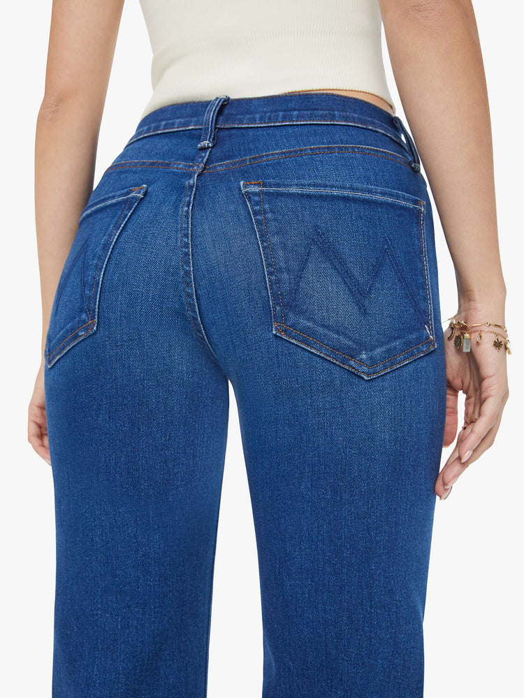 Swatch view of a woman in dark blue wide leg jeans with super subtle whiskering and fading at the knees. Styled with a white tank top.