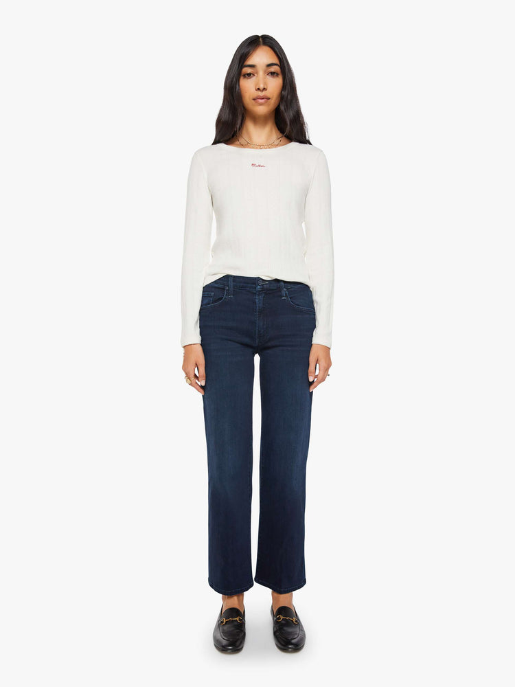 Front view of a woman in dark denim mid-rise jeans with a wide straight leg, zip fly and clean ankle-length inseam.