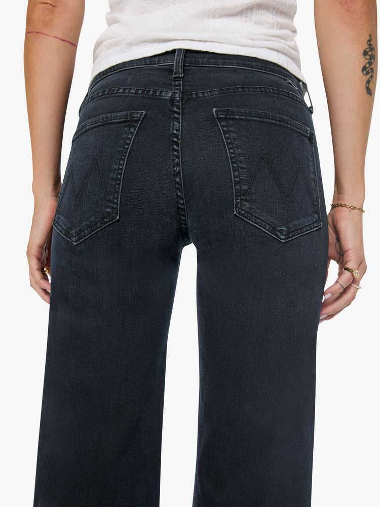 Close up view of a woman in a dark denim mid-rise jean with a wide straight leg, zip fly and clean ankle-length inseam. 