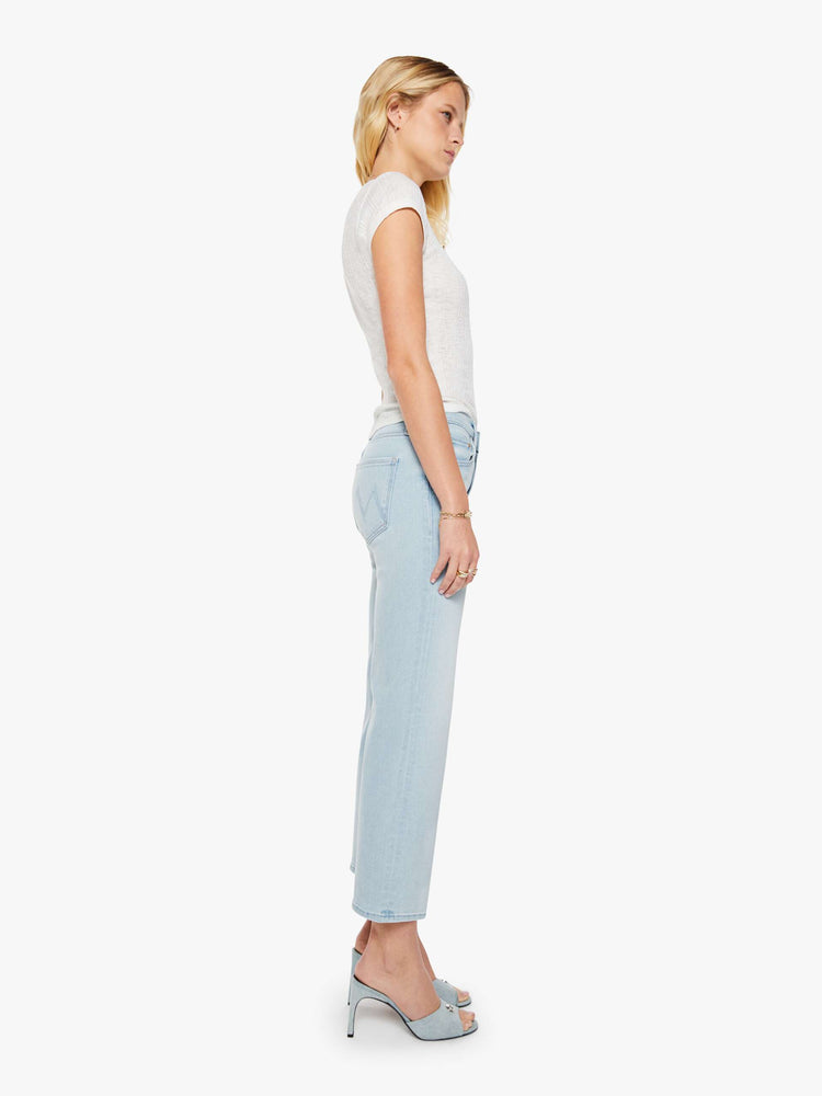 Side view of a woman in a light blue mid-rise jeans with a wide straight leg, zip fly and clean ankle-length inseam. 