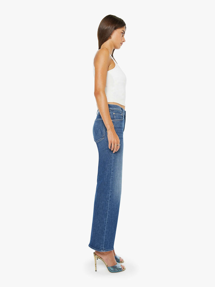 Side view of a mid blue mid-rise jeans with a wide straight leg, zip fly and clean ankle-length inseam.
