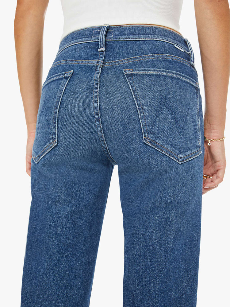 Close up view of a mid blue mid-rise jeans with a wide straight leg, zip fly and clean ankle-length inseam.