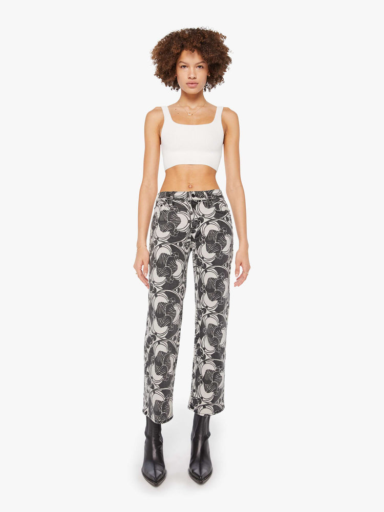Front view of a woman in a faded black and cream oversized graphic print mid-rise pants with a wide straight leg, zip fly and clean ankle-length inseam. 