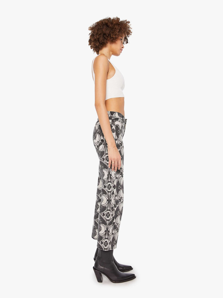 Side view of a woman in a faded black and cream oversized graphic print mid-rise pants with a wide straight leg, zip fly and clean ankle-length inseam. 