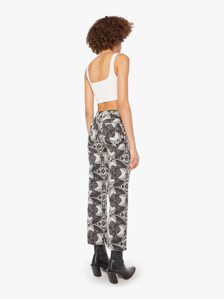 Back view of a woman in a faded black and cream oversized graphic print mid-rise pants with a wide straight leg, zip fly and clean ankle-length inseam. 