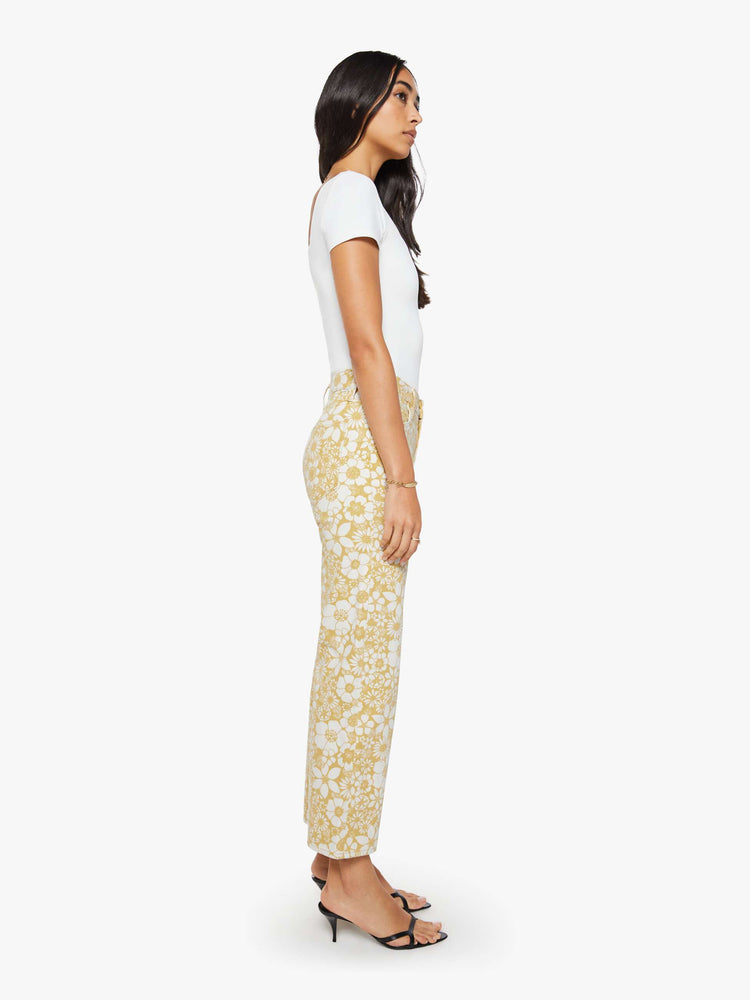 Side view of a woman in a white and golden yellow floral print mid-rise pants with a wide straight leg, zip fly and clean ankle-length inseam.