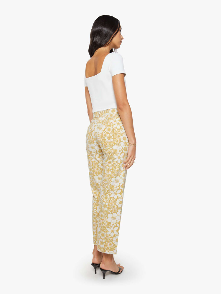 Back view of a woman in a white and golden yellow floral print mid-rise pants with a wide straight leg, zip fly and clean ankle-length inseam.