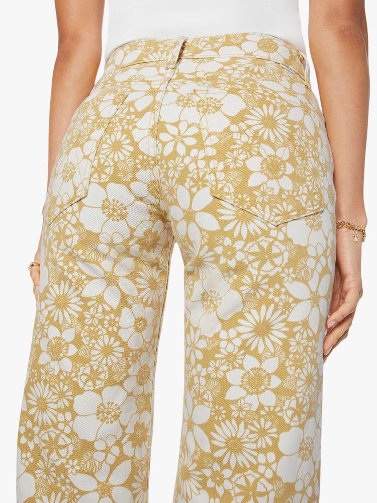 Back view of a woman in a white and golden yellow floral print mid-rise pants with a wide straight leg, zip fly and clean ankle-length inseam.