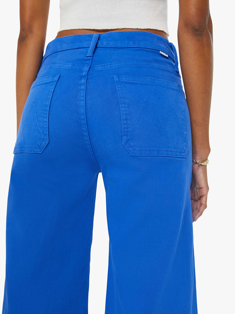 Swatch view of a woman in bright blue high-waisted jeans with a wide leg, and patch pockets, styled with a white tank top.
