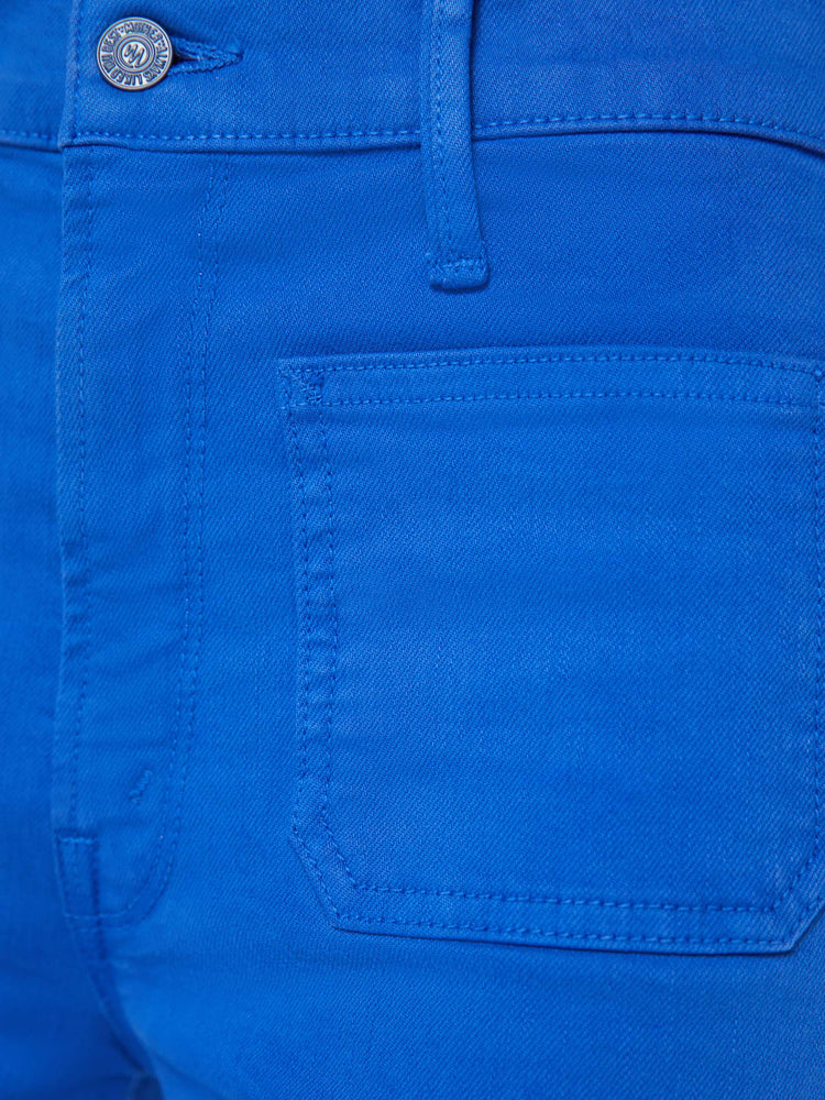 Detailed view of a woman in bright blue high-waisted jeans with a wide leg, and patch pockets, styled with a white tank top.
