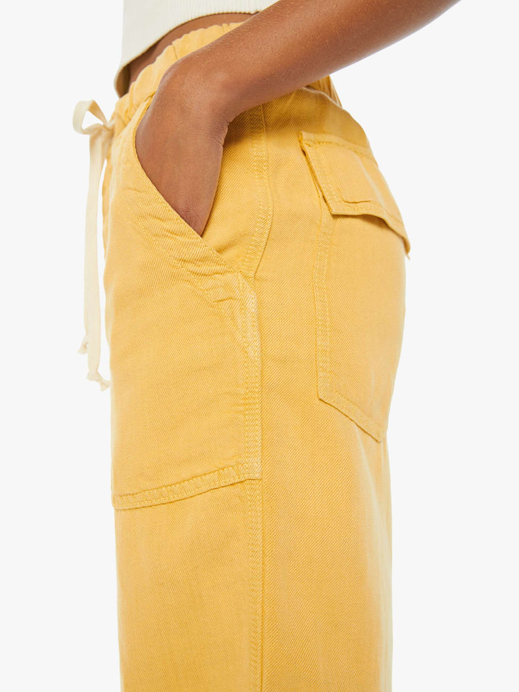 Swatch view of a woman in super high-waisted sunny yellow pants with wide straight leg, an elastic drawstring waistband, button fly, oversized patch pockets and an ankle-length inseam.