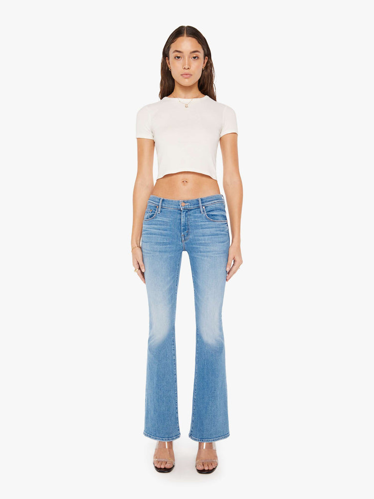 Front view of a woman super low-rise flares have a 32-inch inseam and a clean hem in a mid blue wash.