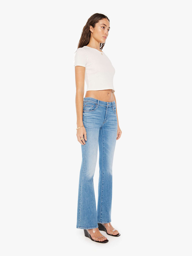 Side angle view of a woman super low-rise flares have a 32-inch inseam and a clean hem in a mid blue wash.