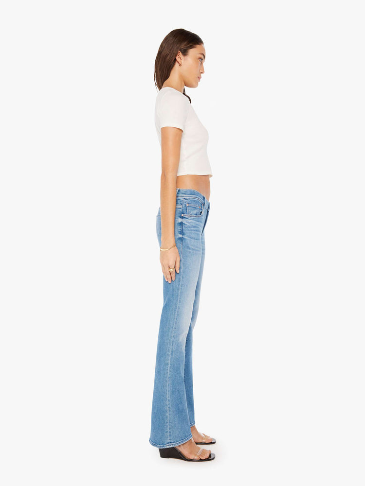 Side view of a woman super low-rise flares have a 32-inch inseam and a clean hem in a mid blue wash.
