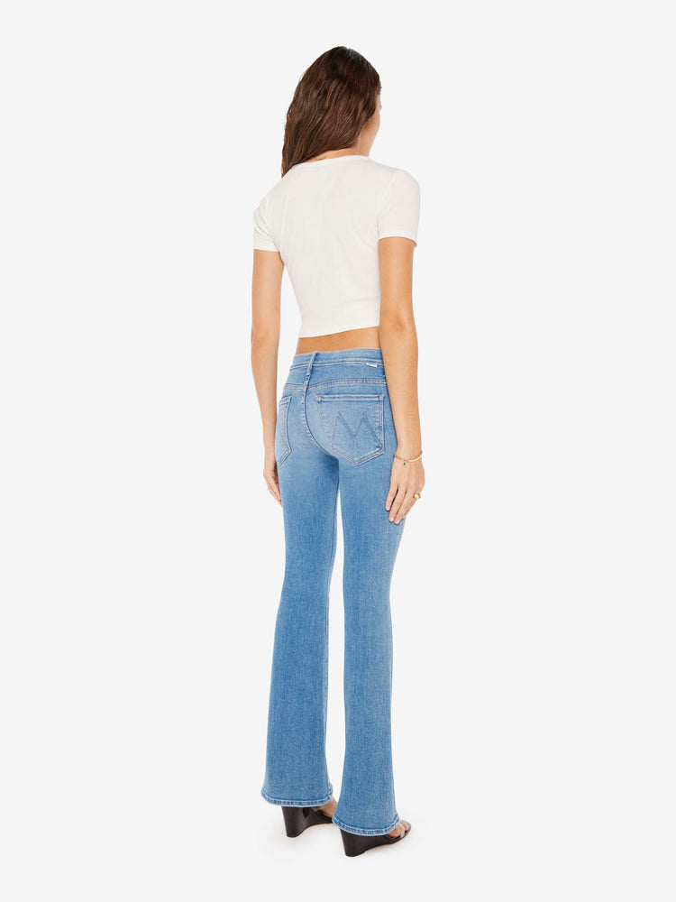 Back view of a woman super low-rise flares have a 32-inch inseam and a clean hem in a mid blue wash.