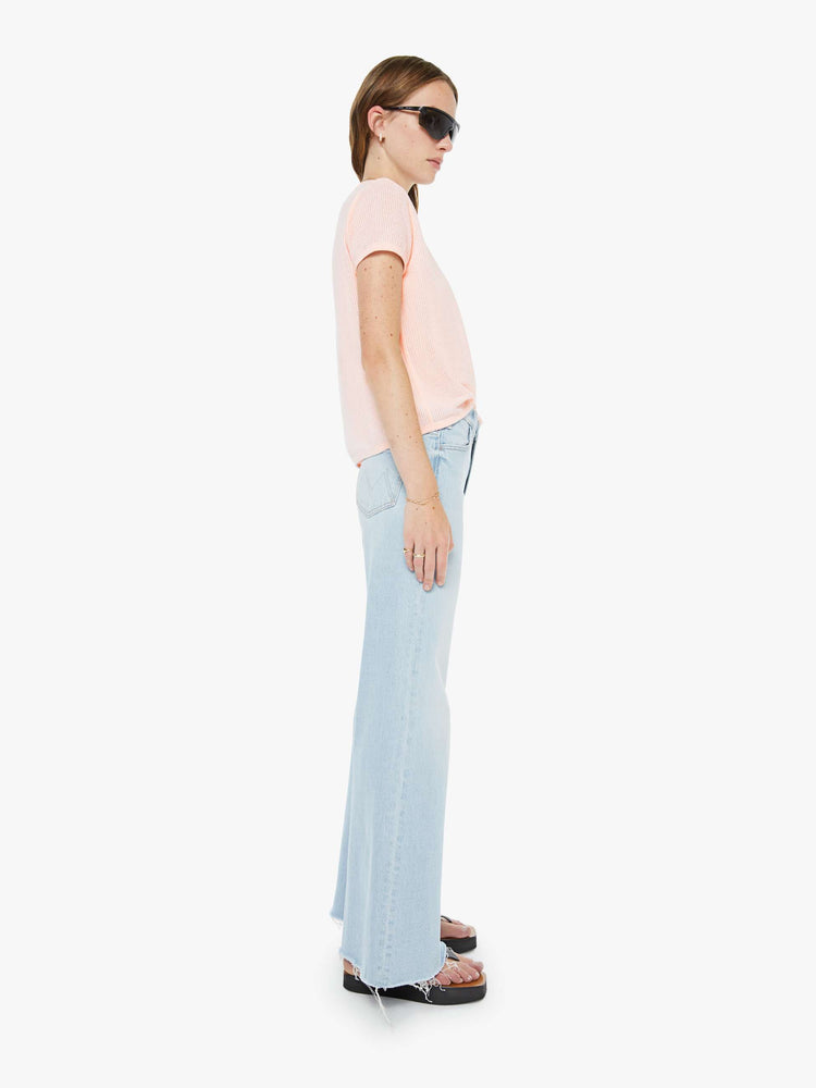 Side view of a woman in a light blue wide leg jeans with a zip fly, high rise, 31-inch inseam and a frayed hem. 