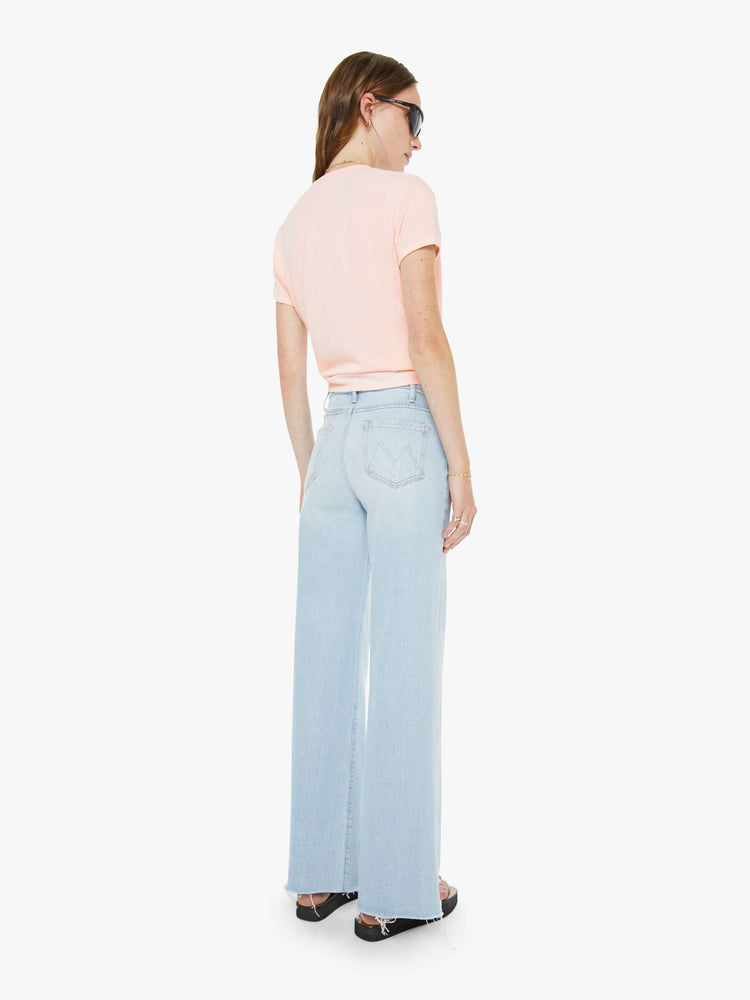 Back view of a woman in a light blue wide leg jeans with a zip fly, high rise, 31-inch inseam and a frayed hem. 