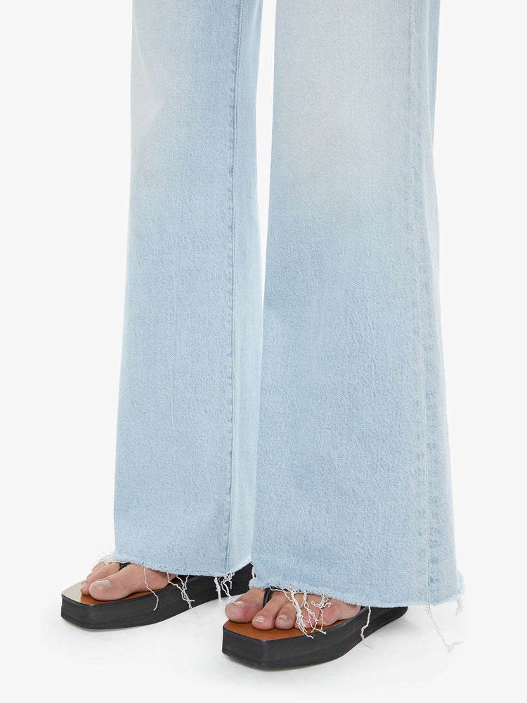 Hem close up view of a woman in a light blue wide leg jeans with a zip fly, high rise, 31-inch inseam and a frayed hem. 