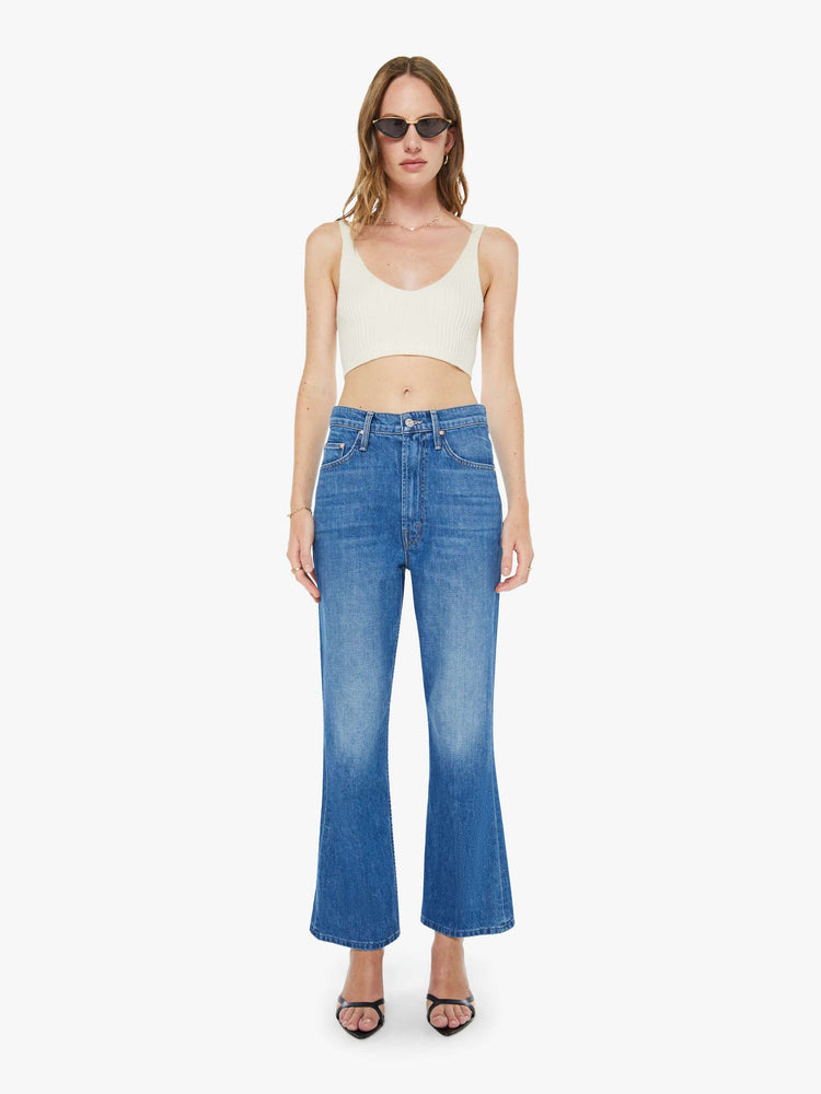 Full body view of a woman in a mid blue designed to sit on the hips with a slouchy fit, these jeans feature a flared leg, zip fly, ankle-length inseam and a super high rise with a slightly dropped crotch.